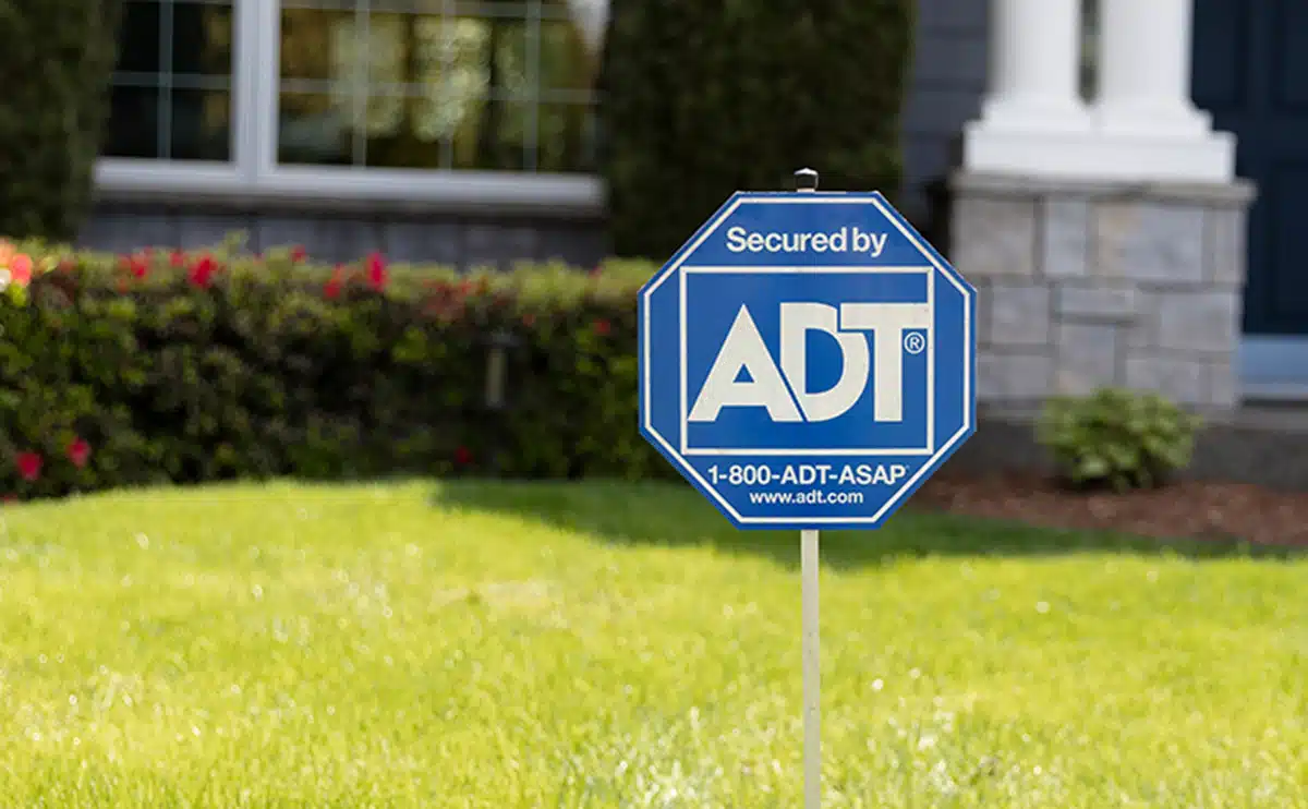ADT Home Security sign in front yard with blurry house in the background.