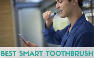 Young man brushing teeth with a smart toothbrush while looking at smartphone. Caption: Best Smart Toothbrush