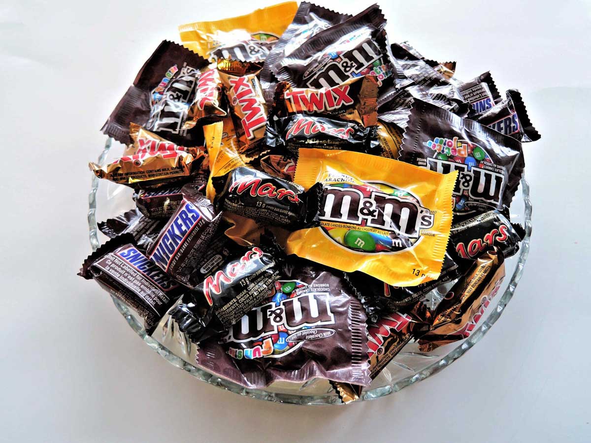 Clear glass bowl filled with halloween candy.