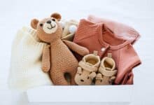 Box of baby clothes and a toy.