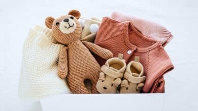 Box of baby clothes and a toy.