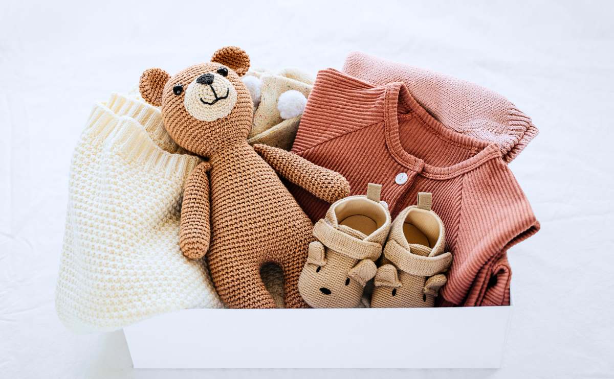 Box of baby clothes and a toy.
