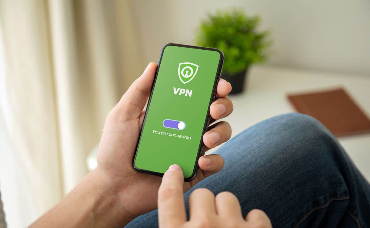 closeup of a man using a VPN on iphone sitting wearing jeans