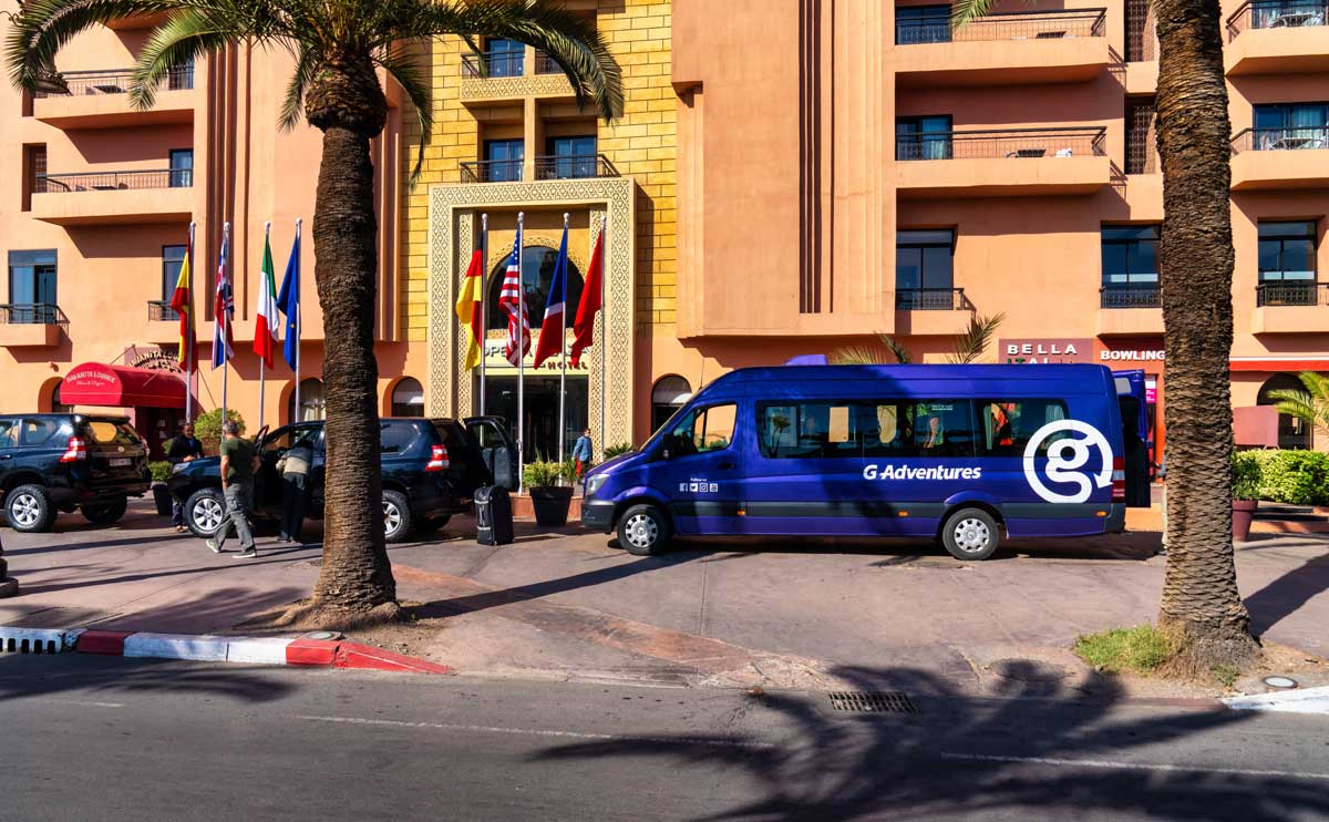 A blue G Adventures tour bus in front of the Opera Hotel in Marrakesh.