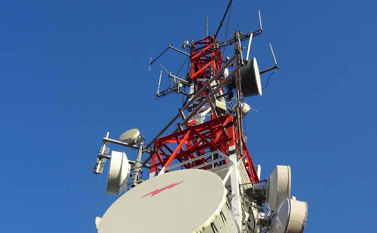 A giant red cell phone radio tower with blue sky background