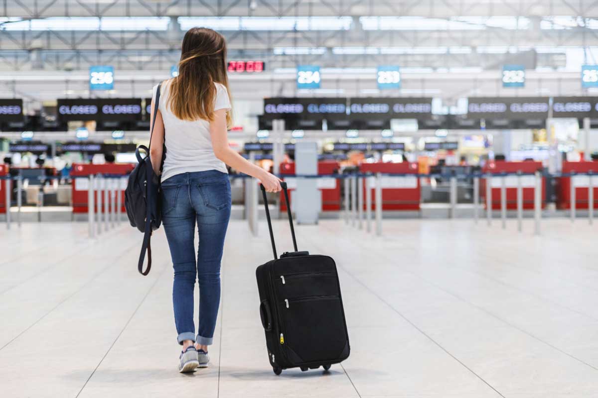 Girl walking through airport with roller bag