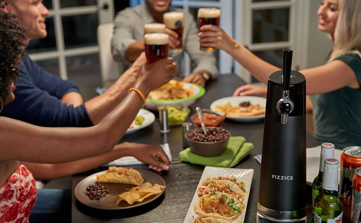Group of people toasting beer sitting at a table with food and Fizzics.