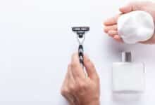 Hand holding razor and handful of shaving cream.