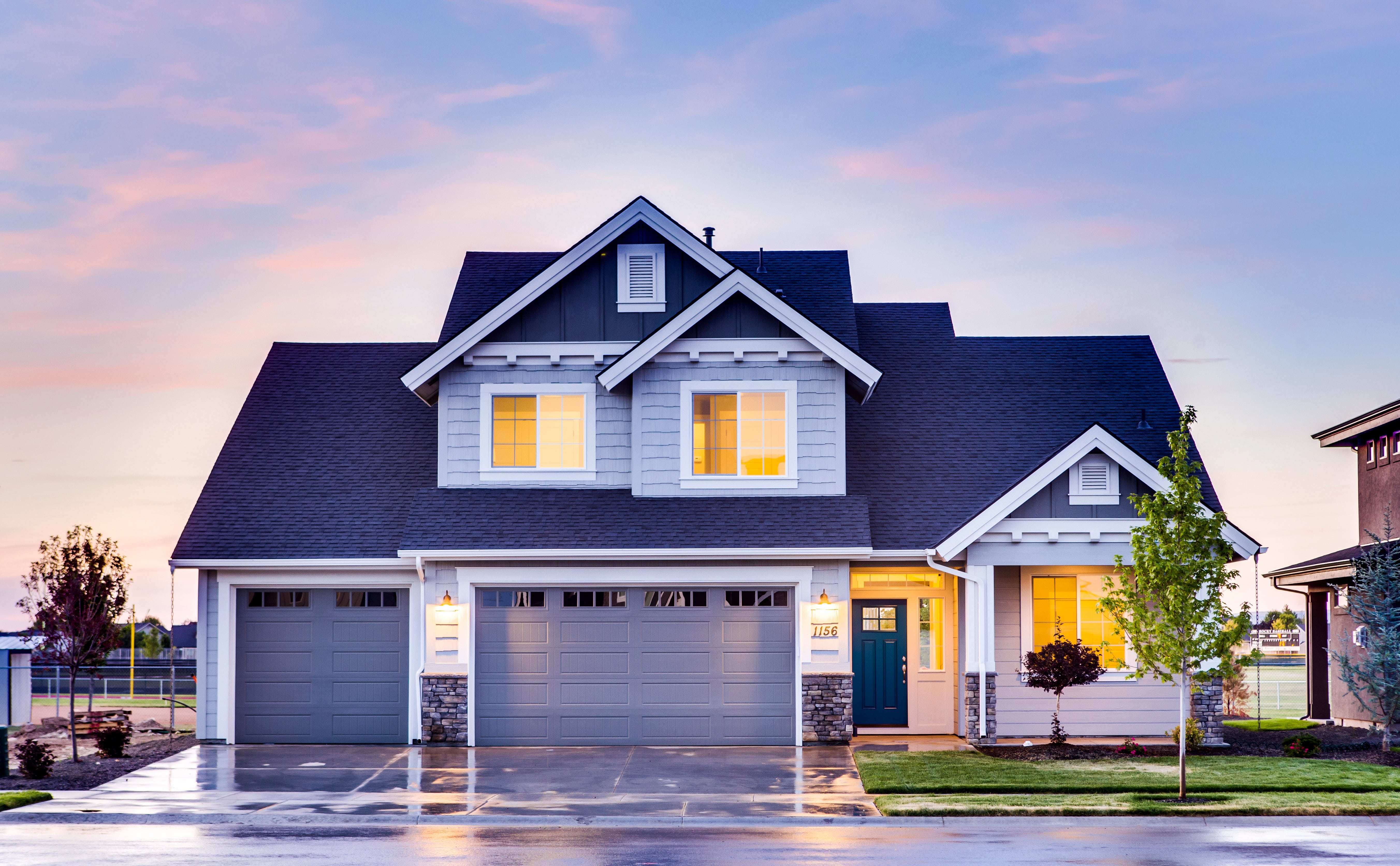 A house at sunset with the interior lights on. 