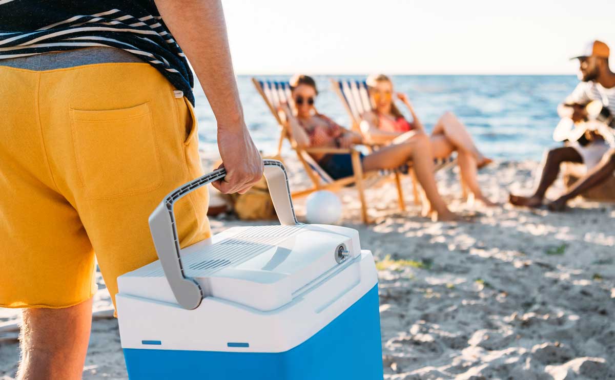 Man carrying cooler to friends on beach