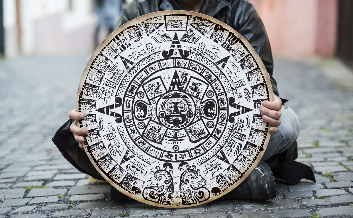 Man is waiting for end of the world sitting on brick path holding Mayan calendar.