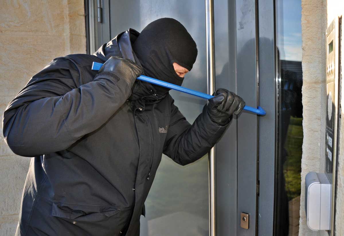 Masked burglar breaking into a home with crowbar