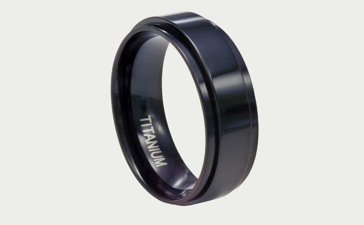 Men's spinner band ring of black oxided titanium is shown isolated on a white background.