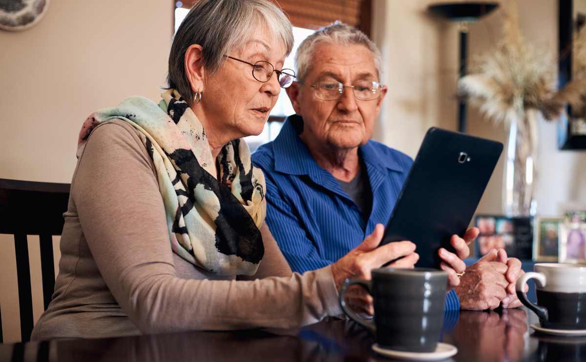 Older couple looking at family history on a tablet sitting together.