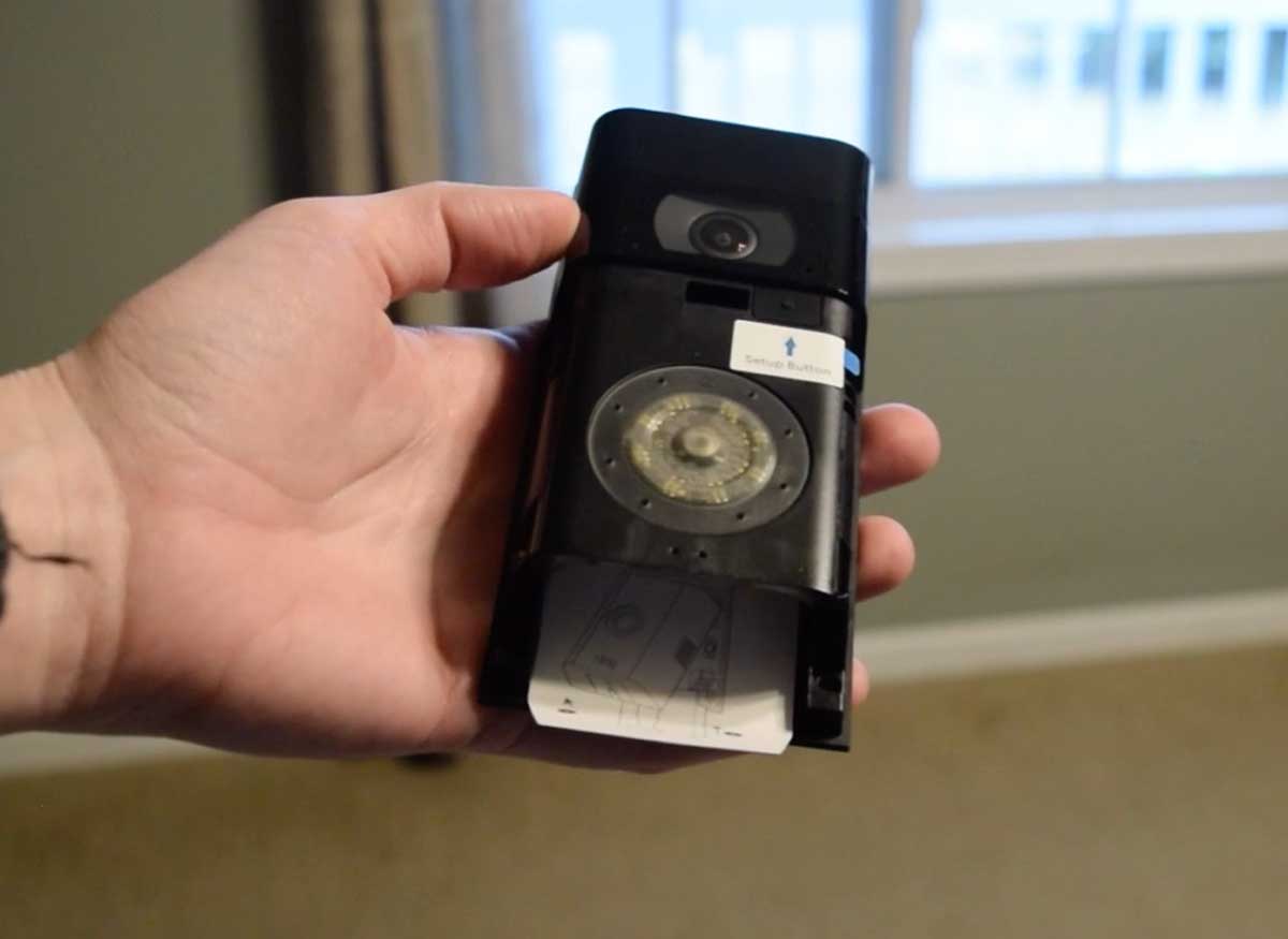 Close-up of Ring doorbell in hand with battery slot exposed.