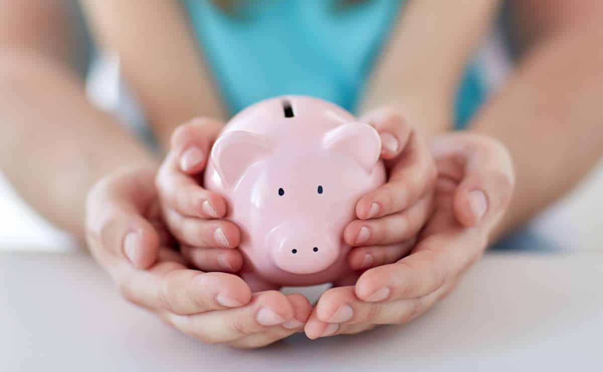 Parent with kid hands holding piggy bank.