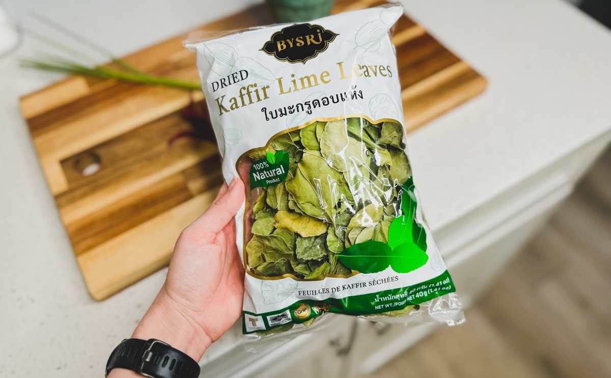 A person holding a bag of dried kaffir lime leaves.