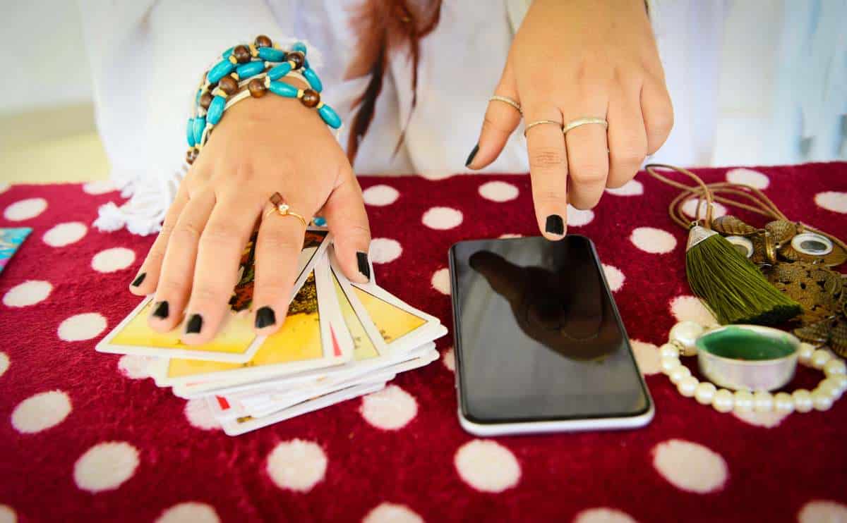 person with tarot cards and phone doing online psychic jpg