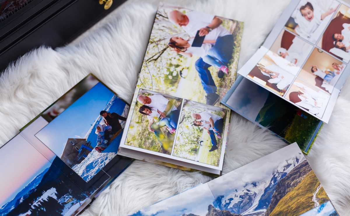 4 photobooks with family and travel memories open on a blanket.