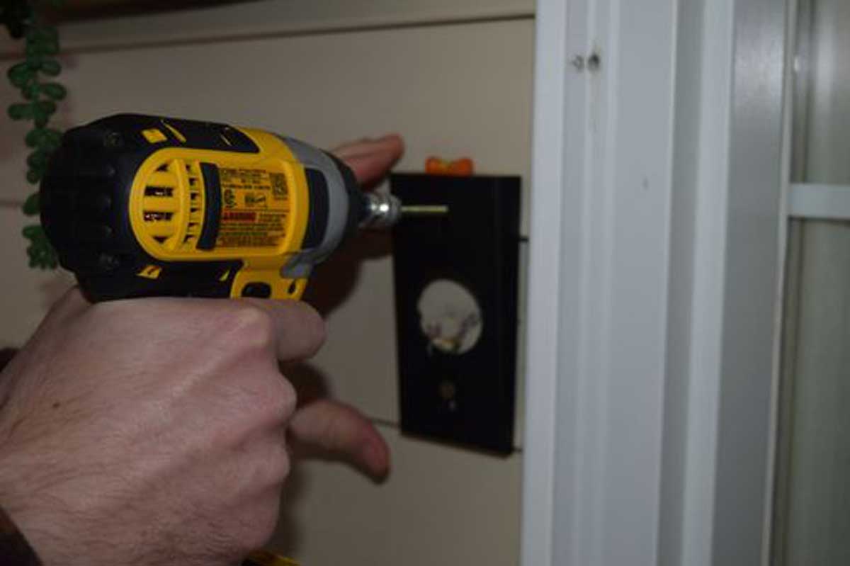 Close-up of hand drilling holes to install the Ring doorbell angled bracket on a door frame.