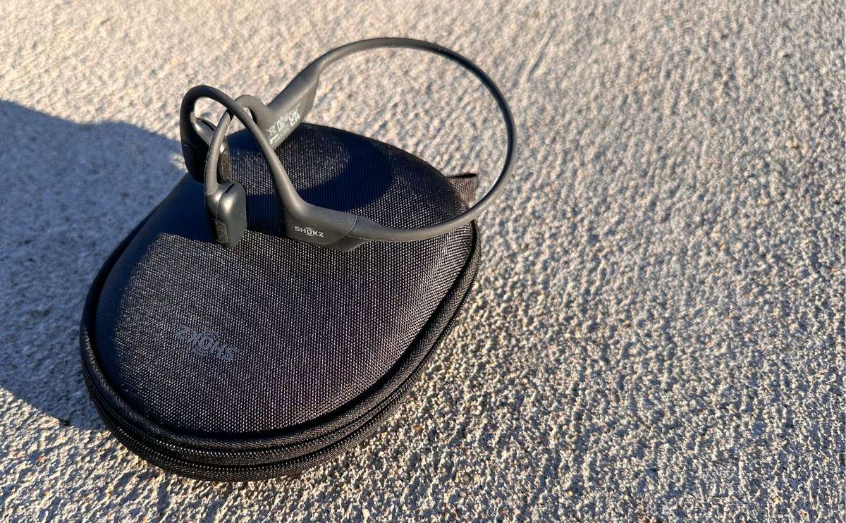 Shokz OpenRun Pro headphones on sidewalk outside in sun.