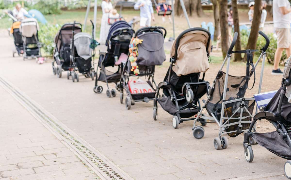 Strollers lined up in a row near the playground.