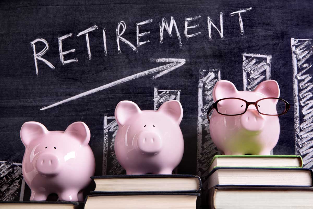 Three piggie banks on books with retirement on chalkboard