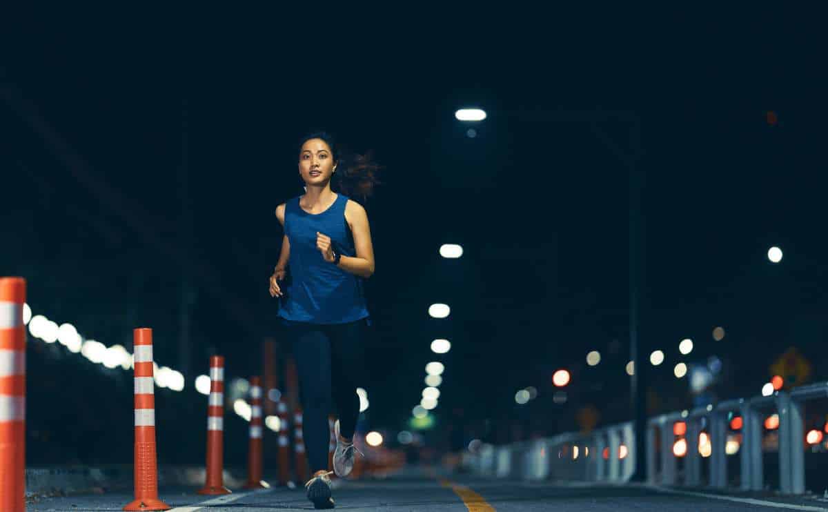 Woman jogging at night on a road.
