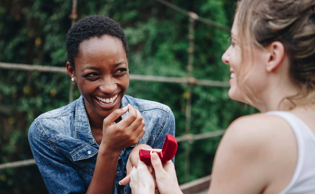 Woman proposing to her happy girlfriend outdoors