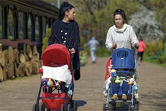 Two women walking kids in strollers from a distance