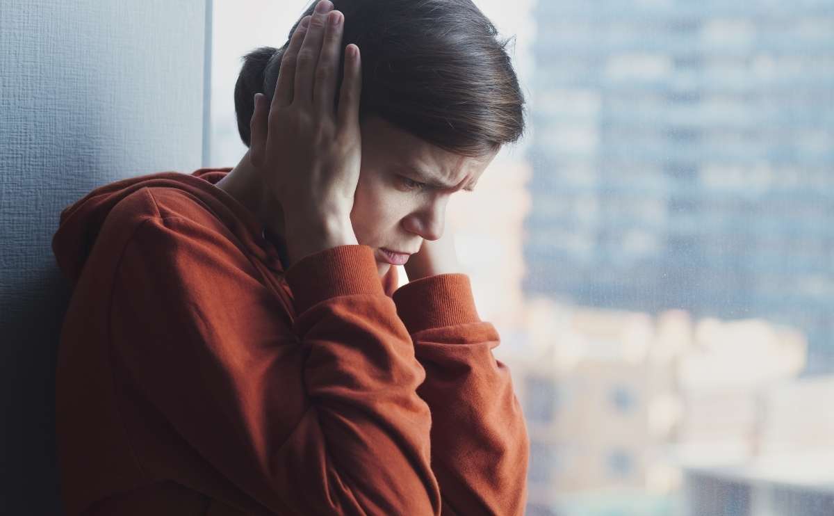 A young sad depressed frustrated autistic woman sitting at home alone suffering from head ache.